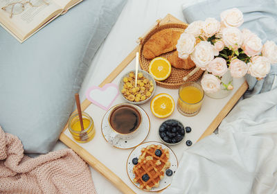 Romantic breakfast with coffee, waffles, orange juice and rose flowers.