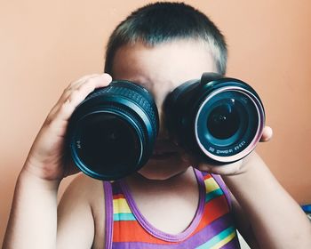 Close-up of boy holding camera lens at home