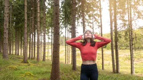 Rear view of woman wearing hat standing in forest