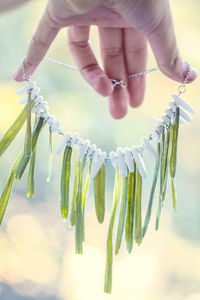 Close up lady holding necklace with grass and white gems concept photo