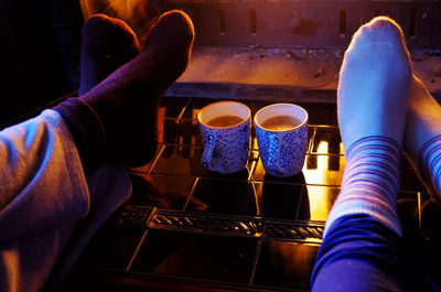 Low section of people wearing socks by coffee cups during winter