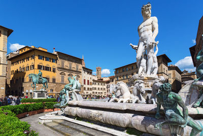 Statues against buildings against clear blue sky