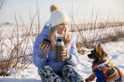 Rear view of woman sitting on snow covered field