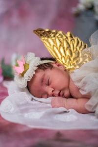 Close-up of cute baby girl with gold wings