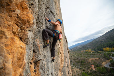 Shirtless man climbing rock