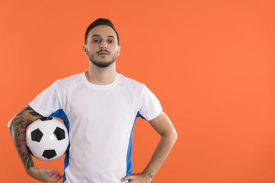 Portrait of young man with arms crossed against yellow background