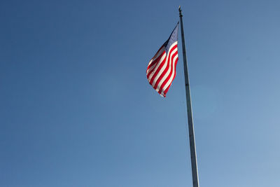 Low angle view of flag against clear blue sky