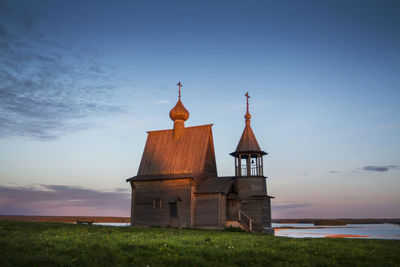 Traditional building on field against sky during sunset