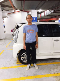 Full length portrait of man standing against car