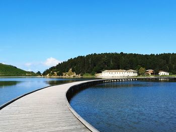 Empty boardwalk over lake on sunny day