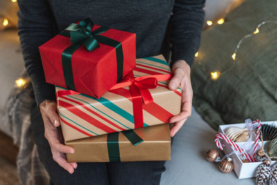 Unrecognizable woman holds a stack of beautifully wrapped christmas presents.