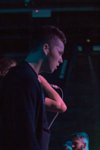 Side view of man looking at illuminated nightclub