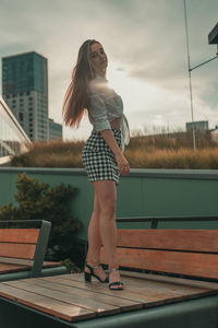 Portrait of woman standing on wooden bench