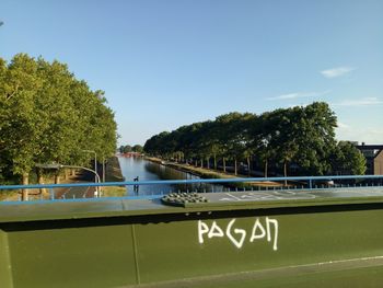 Information sign by trees against sky