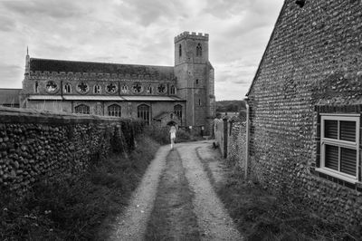 Rear view of girl walking on footpath against st margarets church