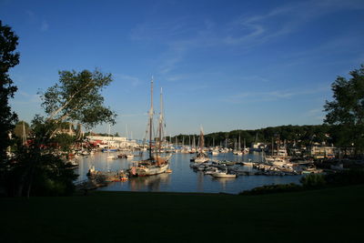 Sailboats moored on harbor against sky at night