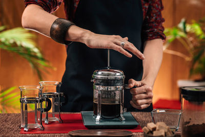 Midsection of woman making coffee in cafe