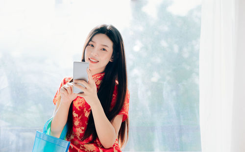 Portrait of smiling young woman using mobile phone