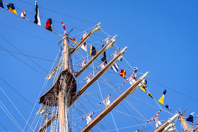 Low angle view of flags on mast against clear blue sky