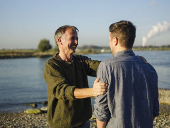 Men standing on shore against sky