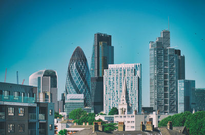 Modern buildings in city against clear blue sky