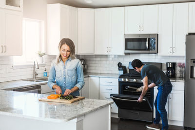 Friends standing in kitchen at home