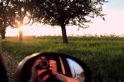 Reflection of man photographing on side-view mirror