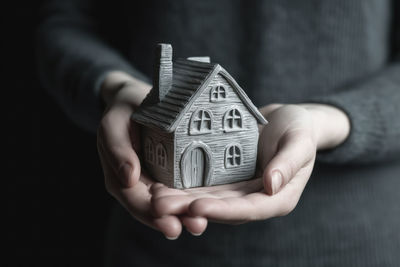 Midsection of man holding model house