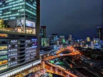 Illuminated modern buildings in city against sky at night