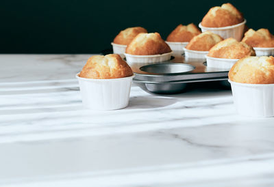 Muffins removed from a muffin tin on a marble background