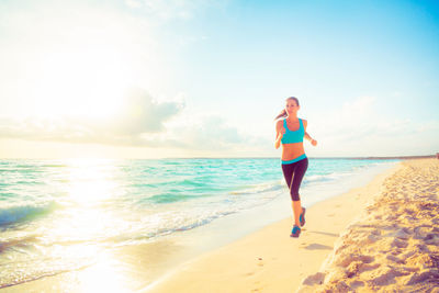 Full length of woman standing at beach against sky