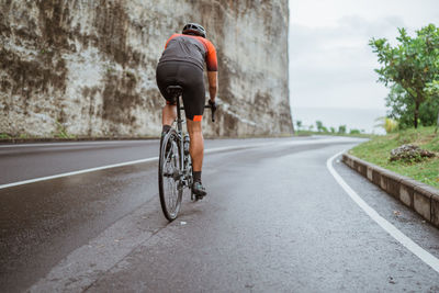 Rear view of man riding bicycle on road