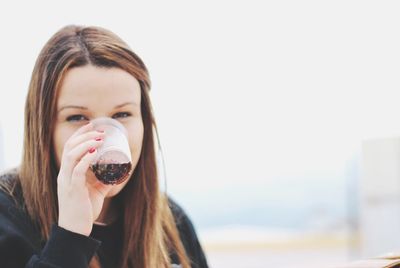 Portrait of young woman with long hair having drink