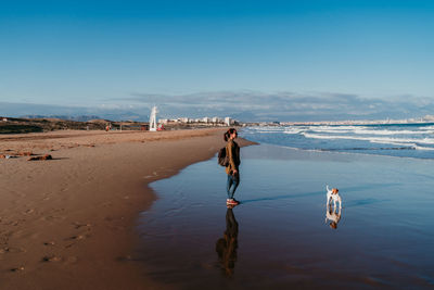 Rear view of people on beach against sky