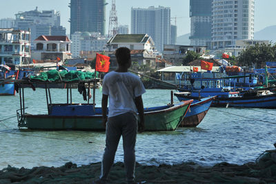 Rear view of man standing on boat in city