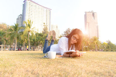 Woman reading book in park against clear sky