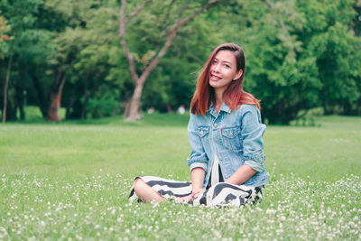 Portrait of young woman sitting on field