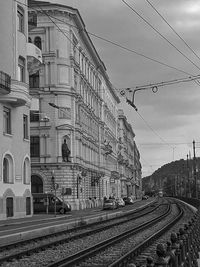 Railroad tracks by buildings in city against sky