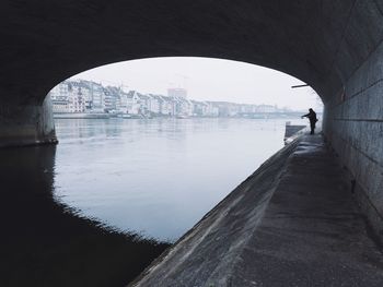 Rear view of man walking on bridge over river