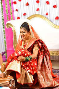 Full length of smiling bride wearing red sari looking away on stage