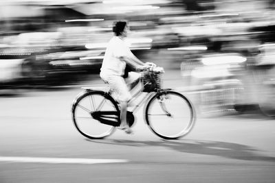 Blurred motion of woman riding bicycle on street 