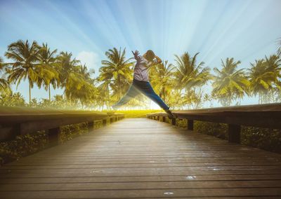 Man jumping on road with palm trees
