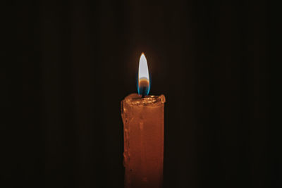 Close-up of illuminated candle against black background