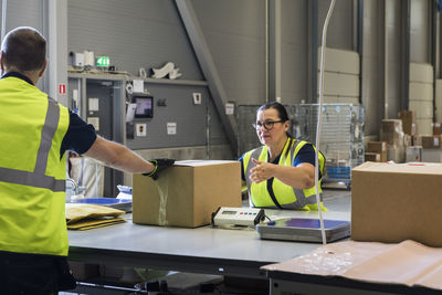 Coworkers packing merchandise on desk at warehouse