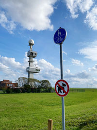 Road sign on field against sky
