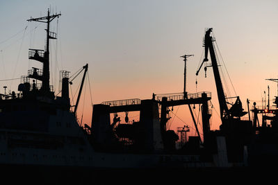 Silhouettes of ships and container cranes in sea port, sunset background. industrial landscape