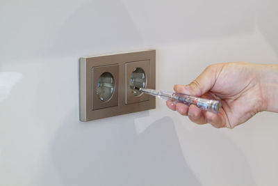 Midsection of man holding mobile phone against wall