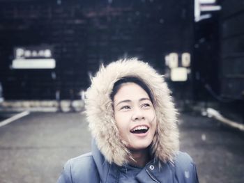 Close-up of smiling young woman standing on road during winter