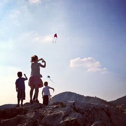 Children playing on mountain against sky