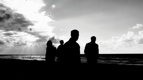 Silhouette men on beach against sky